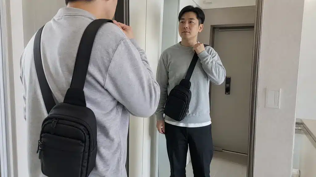 거울 앞에서 무브랜드 바이커 크로스백 핏을 확인하는 이미지